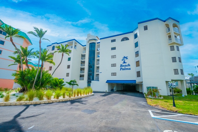 Exterior view of the Beach Palms building with palm trees and a clear blue sky.